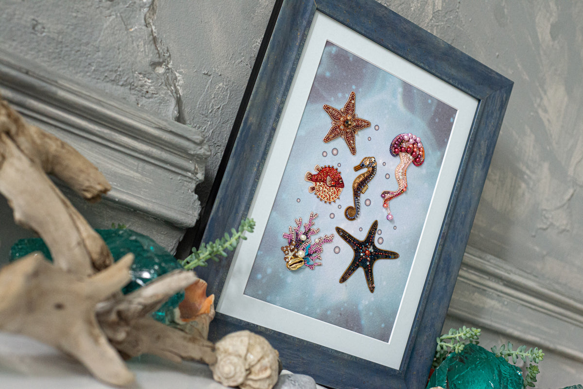 a framed artwork depicting various marine life, including a starfish, a jellyfish, and a seahorse, set against a blue background.