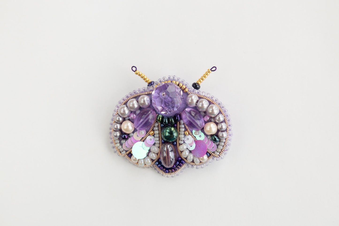 a close up of a brooch on a white surface