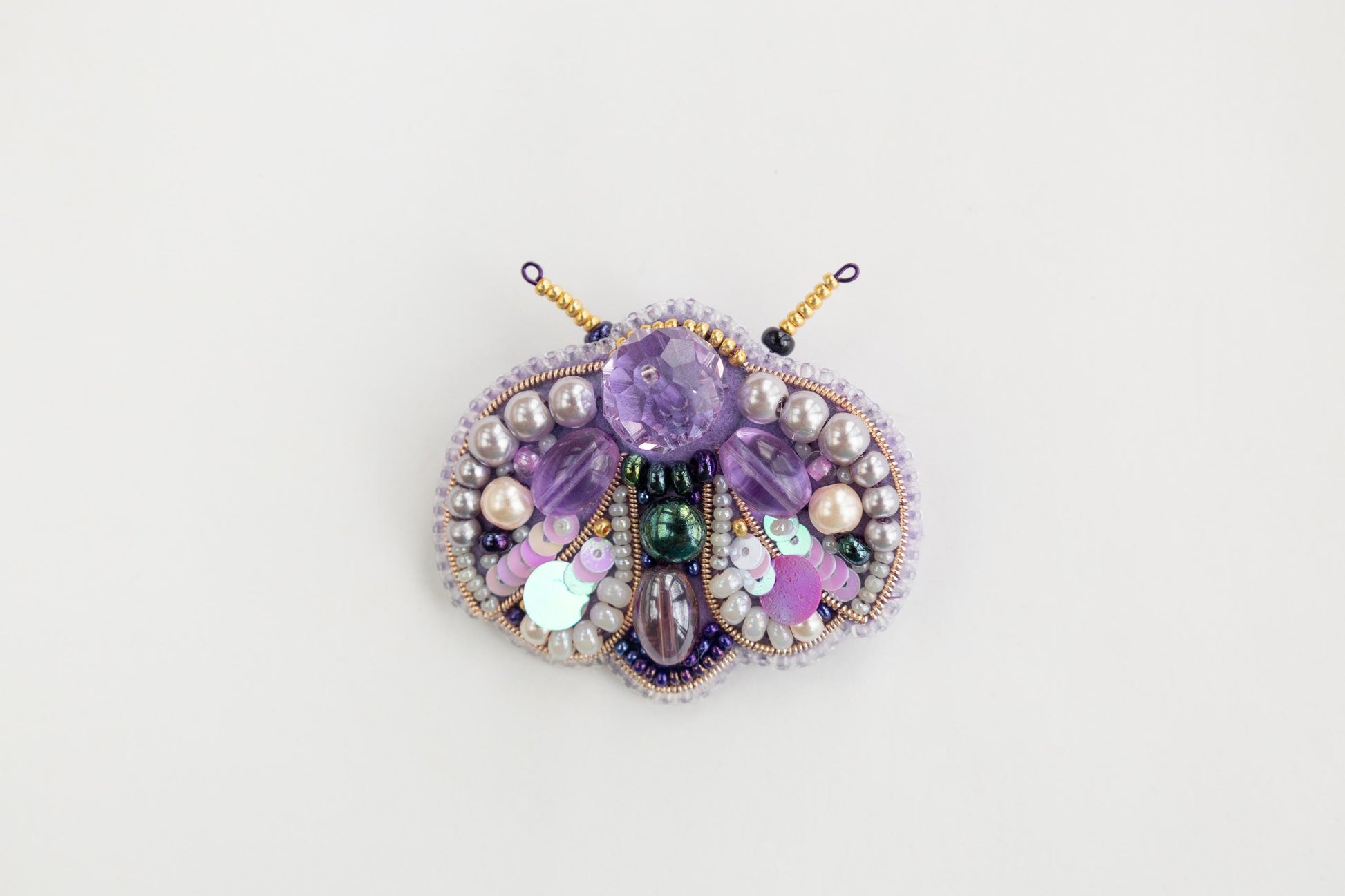 a close up of a brooch on a white surface