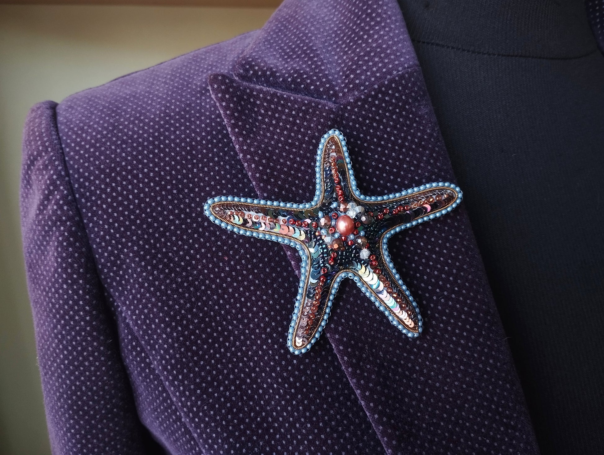 A close-up image of a purple jacket with a starfish brooch on the lapel.