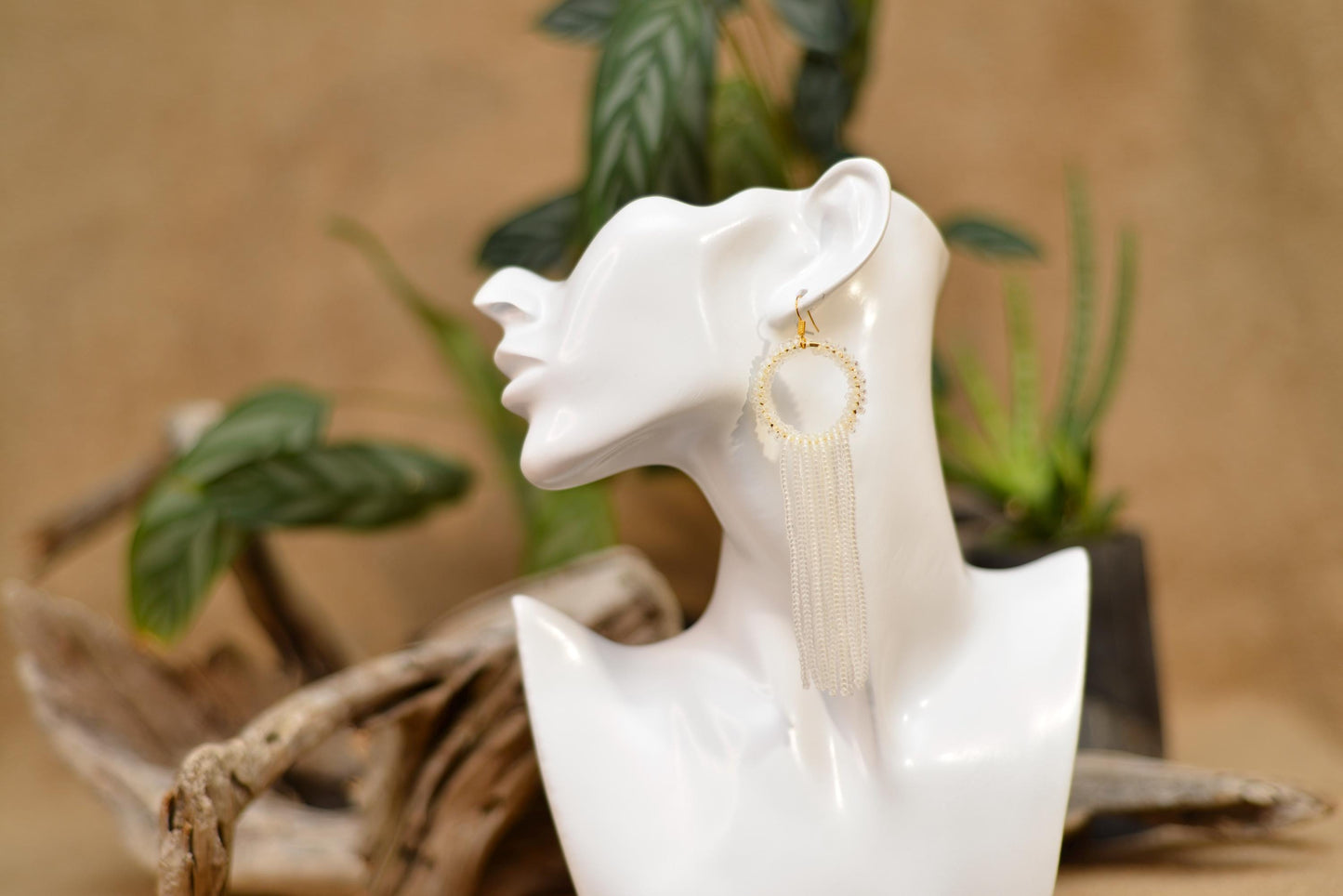 a white sculpture of a woman&#39;s head with a pair of earrings on it