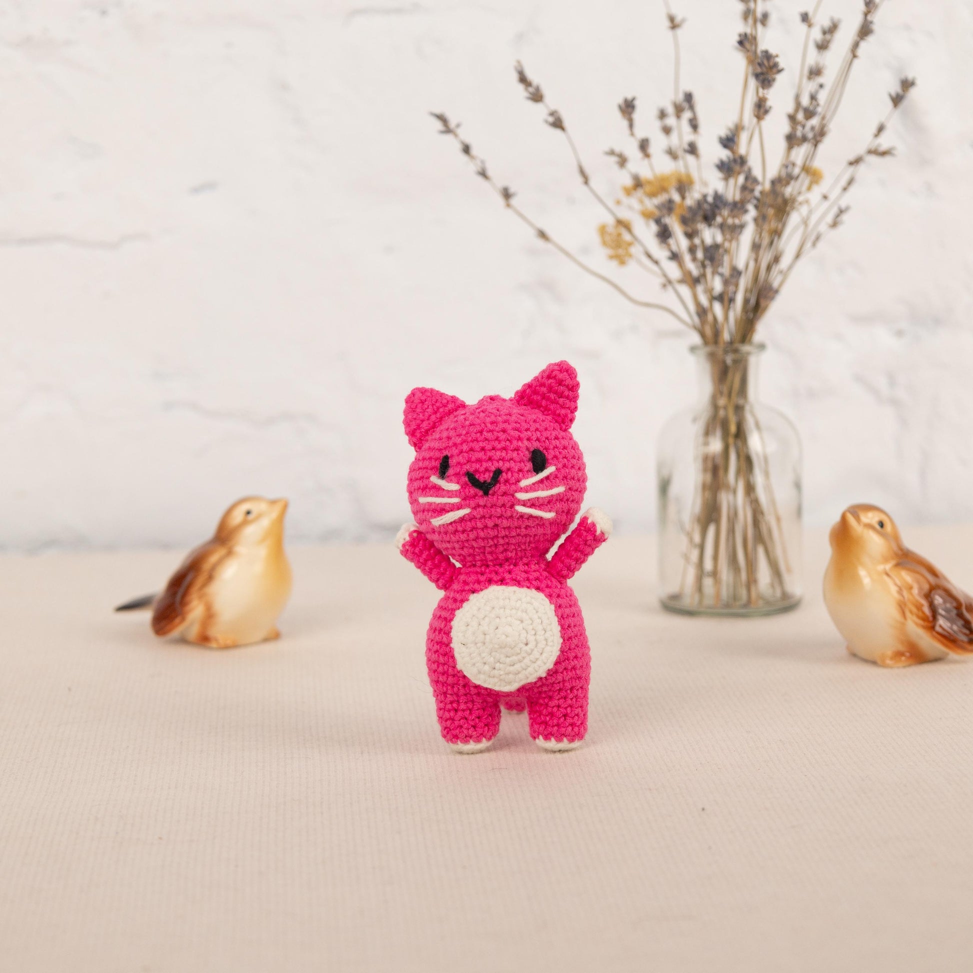a crocheted cat and two birds are next to a vase with flowers