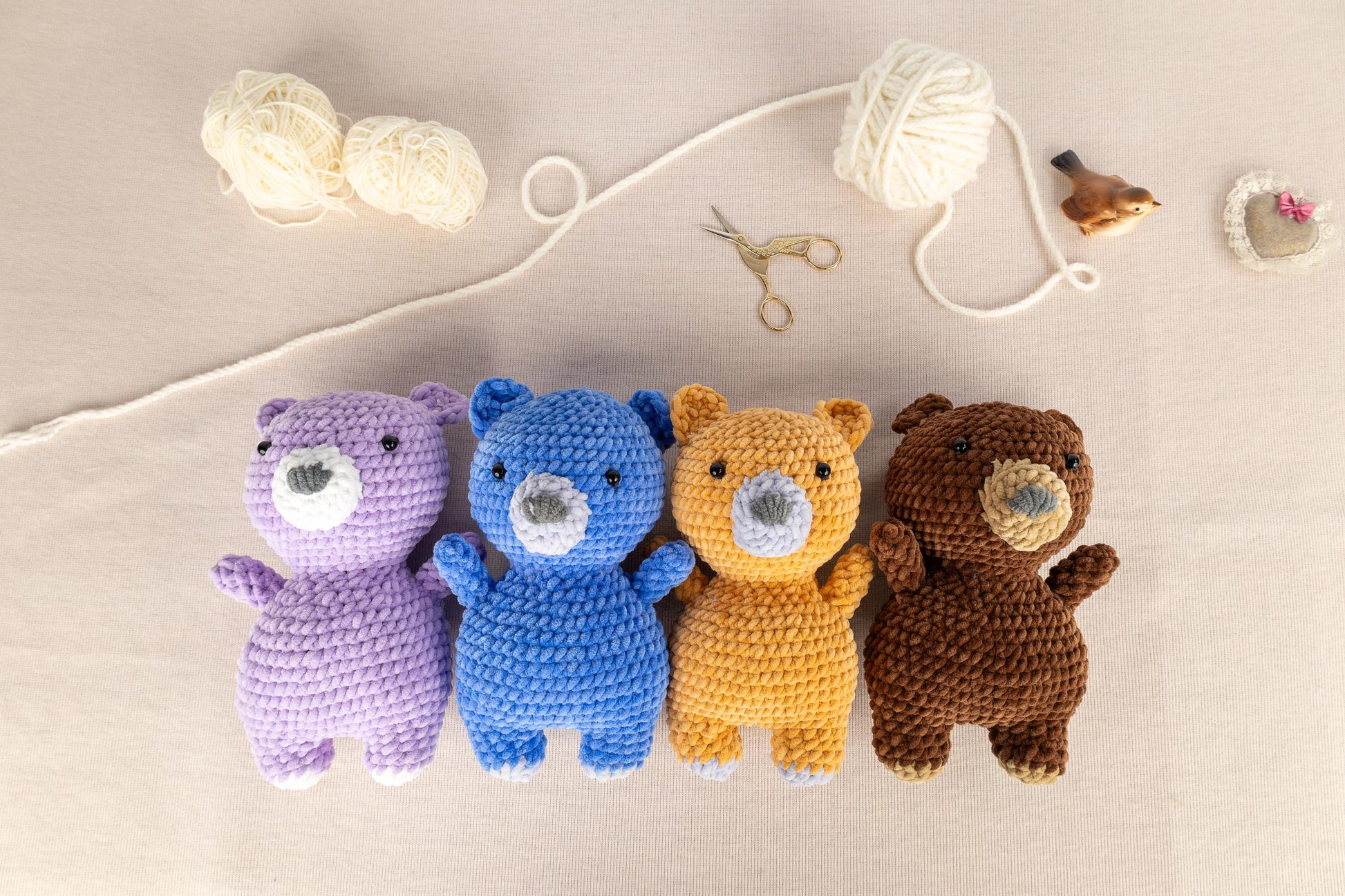 a group of crocheted teddy bears sitting next to a ball of yarn