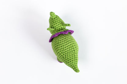 a crocheted green stuffed animal with a purple hat