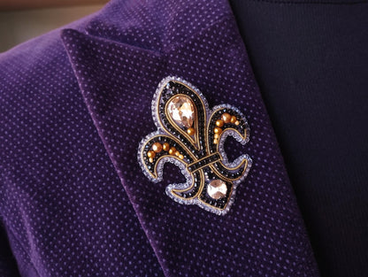 A close-up view of a purple jacket with a decorative fleur-de-lis brooch on the lapel.