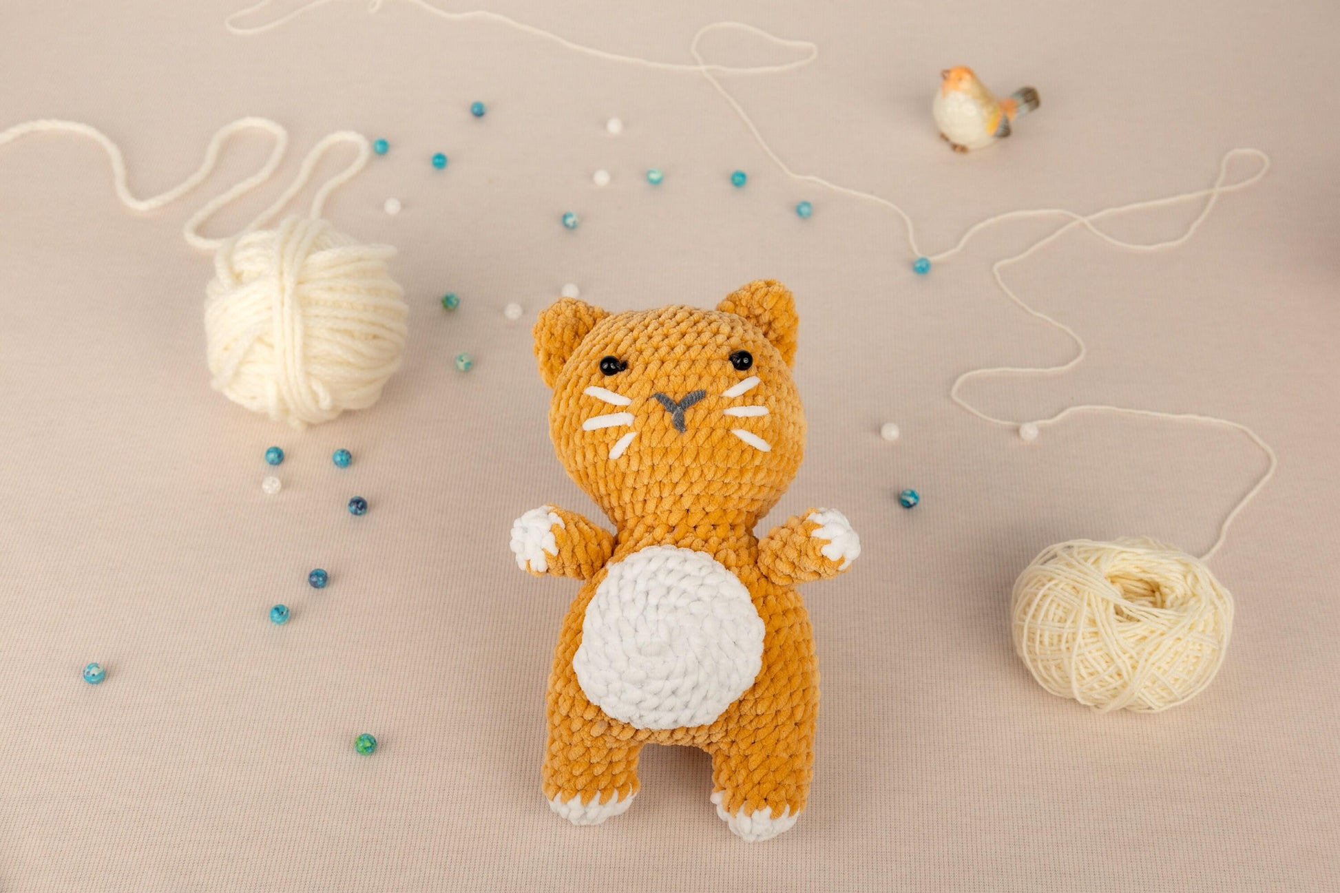 a crocheted cat sitting next to a ball of yarn
