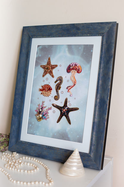 a framed artwork of various sea creatures, including a starfish, a jellyfish, and a seahorse, set against a blue background.