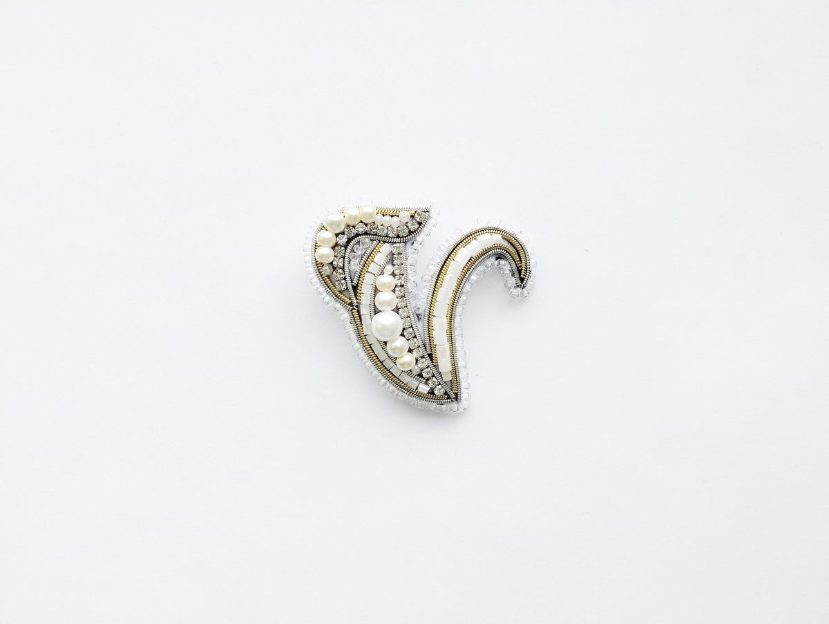 A decorative piece of jewelry, possibly a brooch or pendant, is shown against a plain white background.