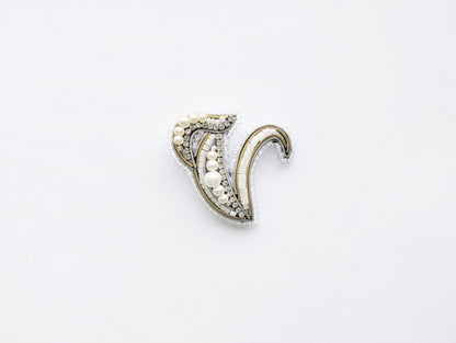 A decorative piece of jewelry, possibly a brooch or pendant, is shown against a plain white background.