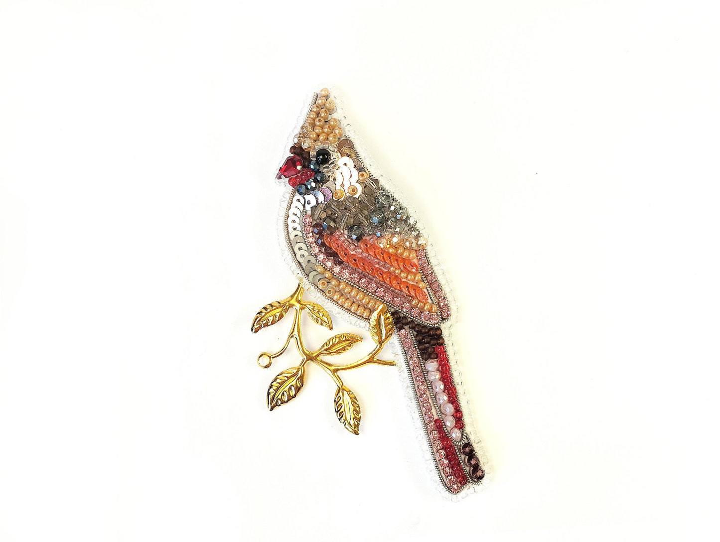 a beaded bird brooch sitting on top of a white surface