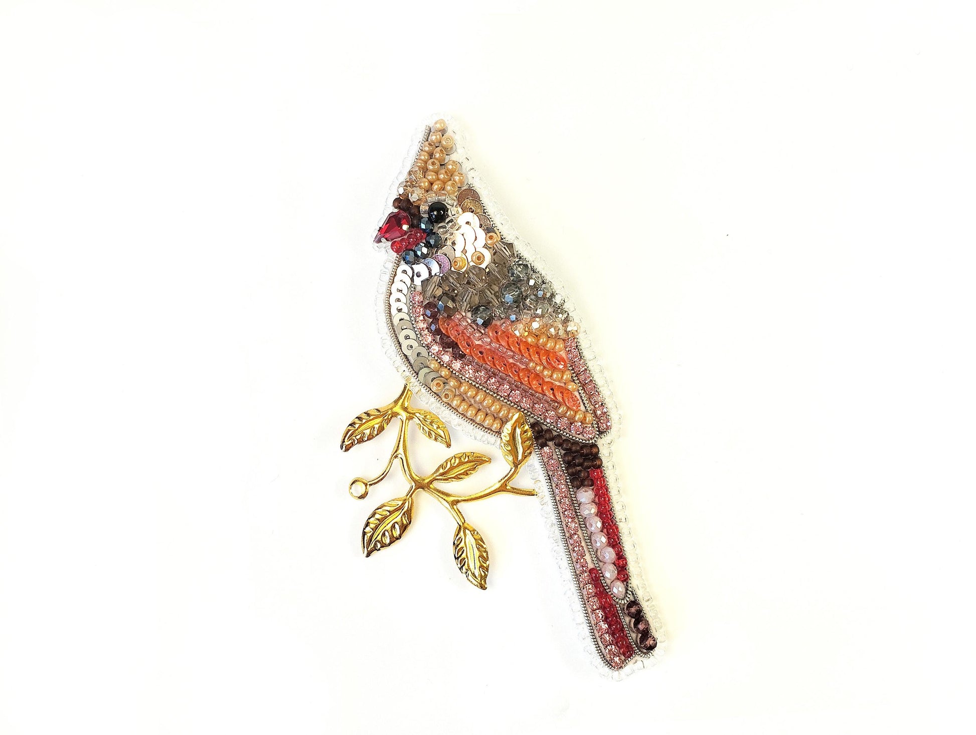 a beaded bird brooch sitting on top of a white surface