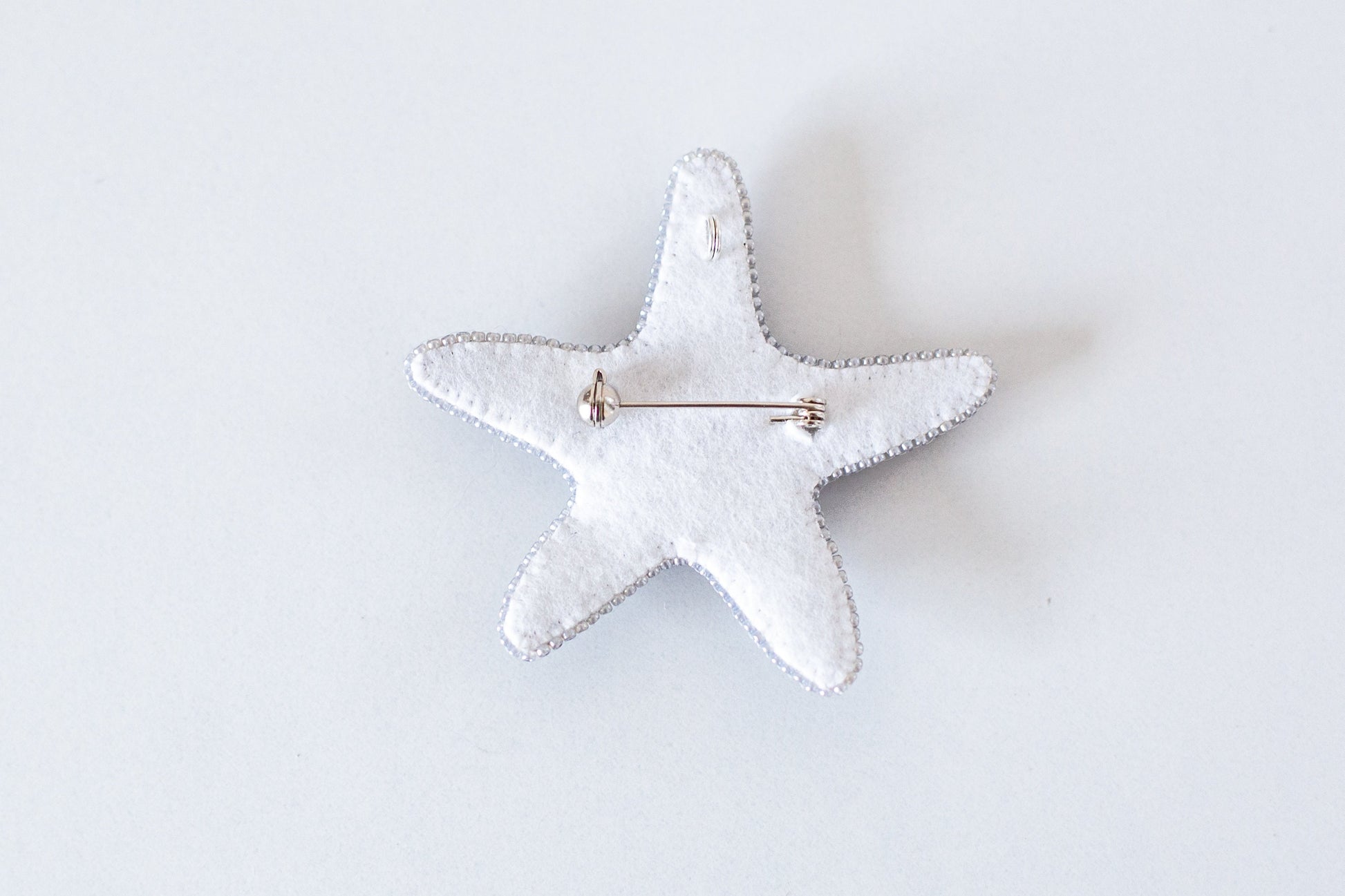 a white starfish brooch with a pin on it