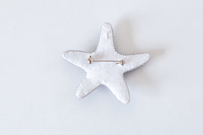 a white starfish brooch with a pin on it