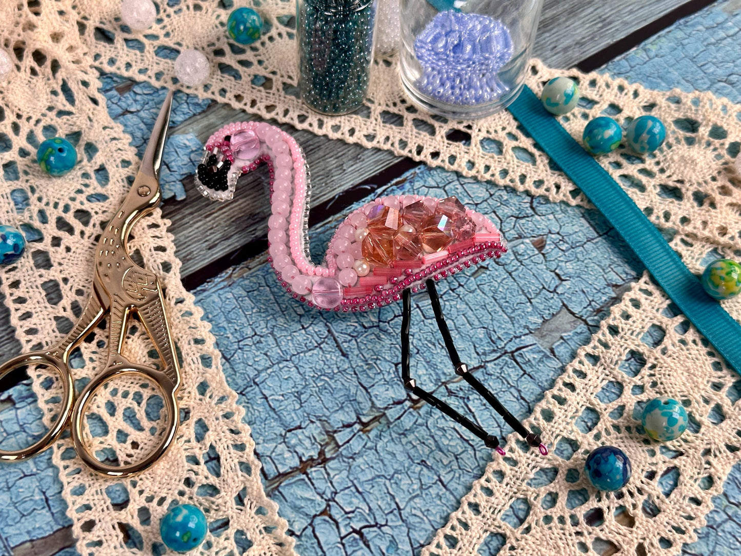 a pink flamingo sitting on top of a table next to a pair of scissors