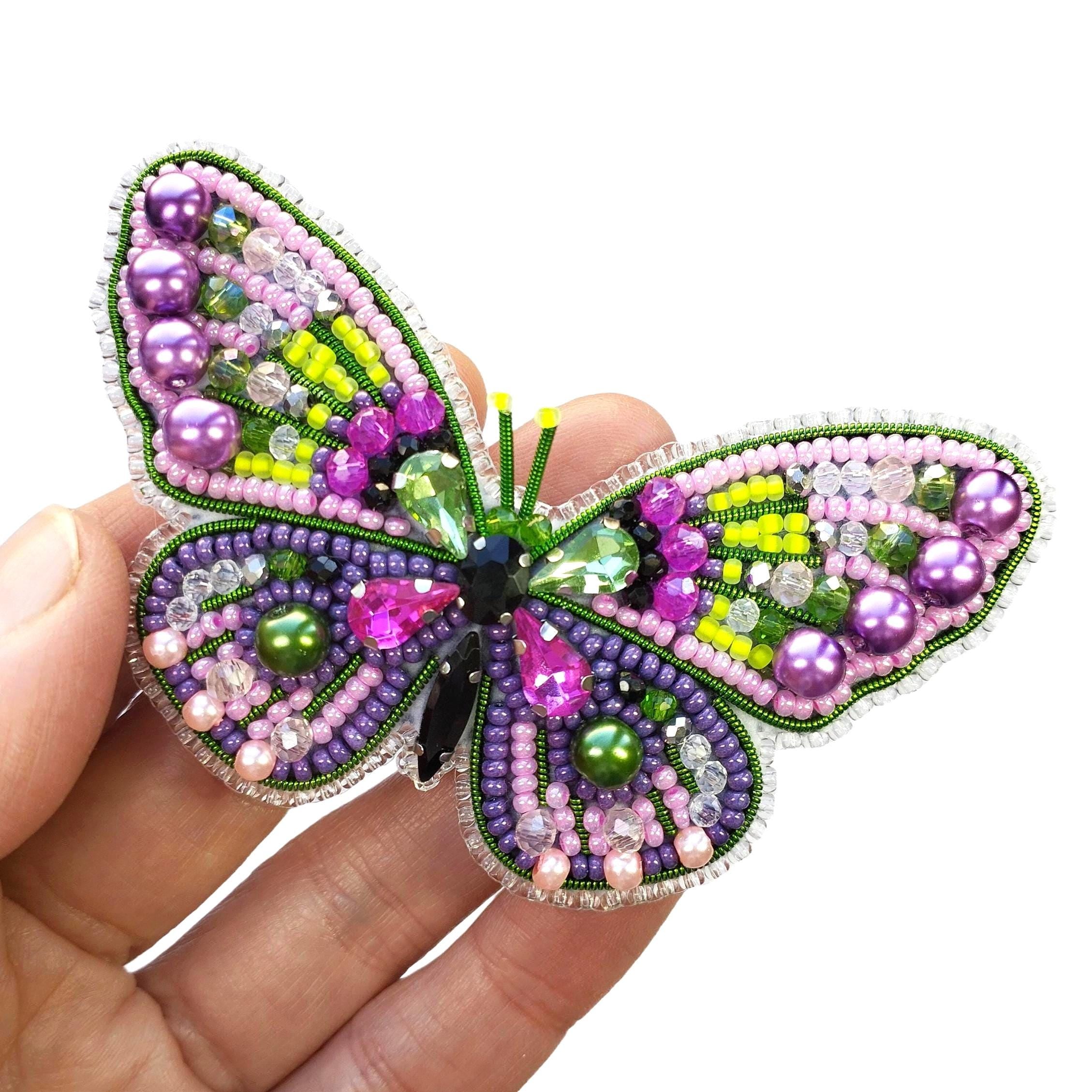 a hand holding a colorful beaded butterfly