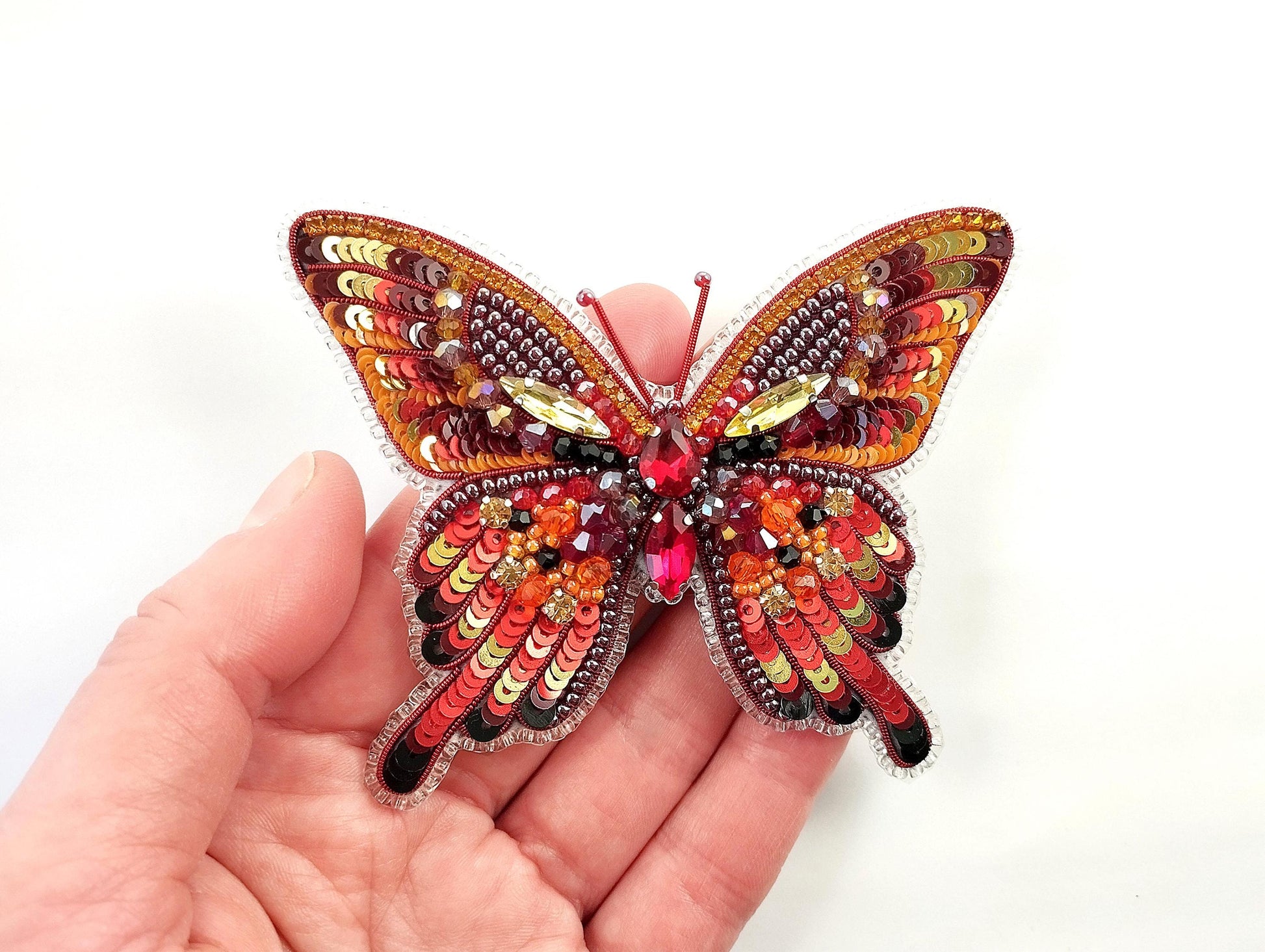 a hand is holding a colorful butterfly brooch
