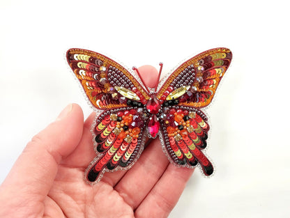 a hand is holding a colorful butterfly brooch