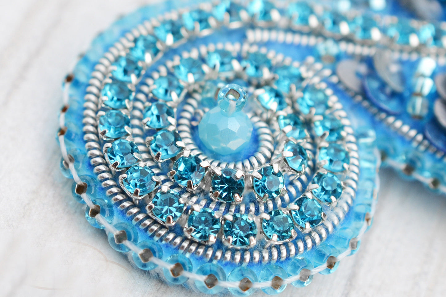 a close up of a blue and silver brooch