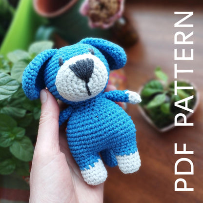 a hand holding a small blue crocheted teddy bear