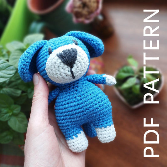 a hand holding a small blue crocheted teddy bear