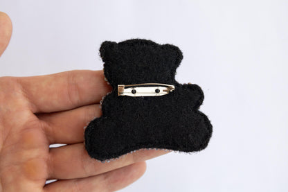 a person holding a black bear brooch in their hand