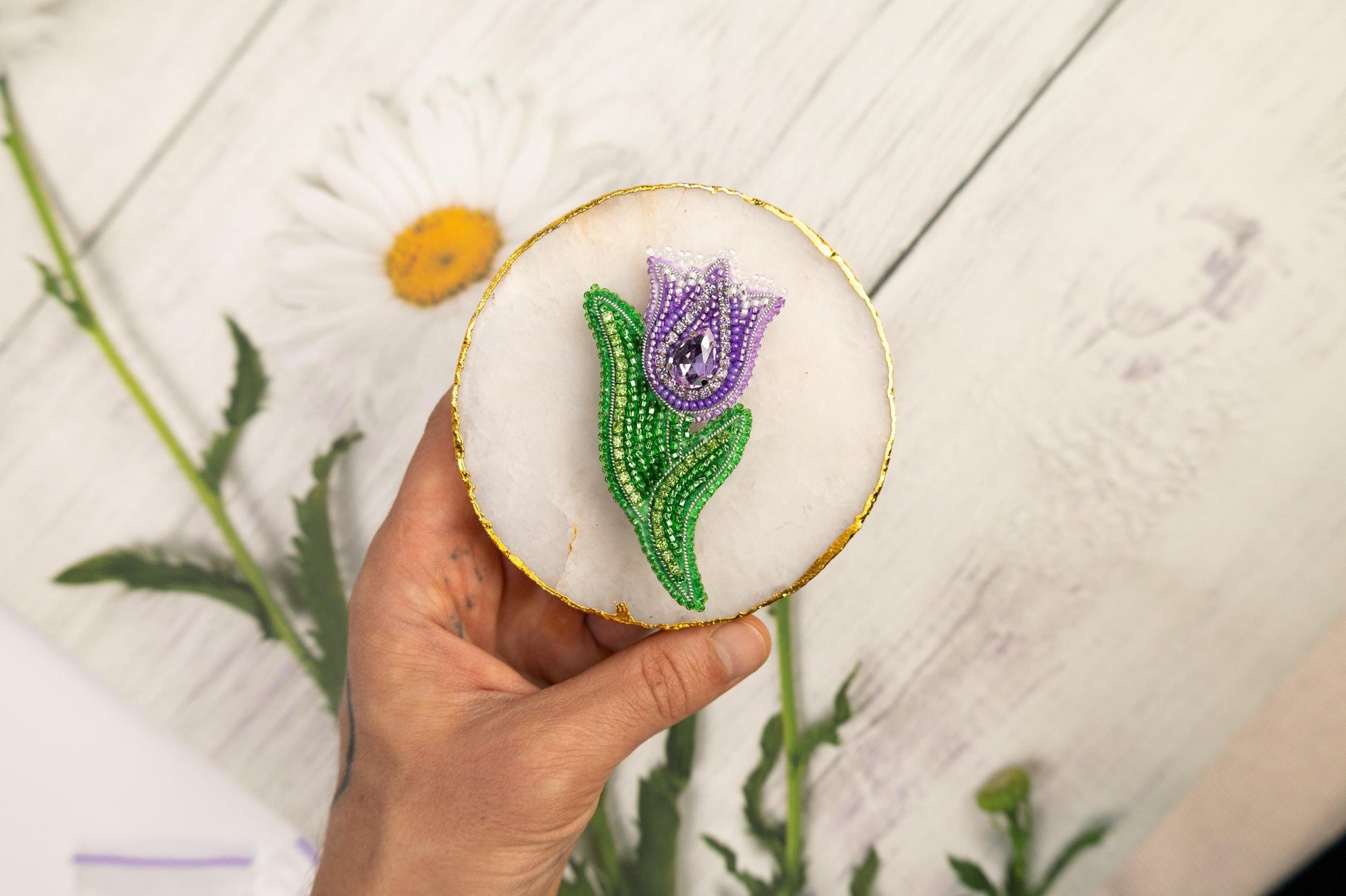 a hand holding a decorated cookie with a flower on it