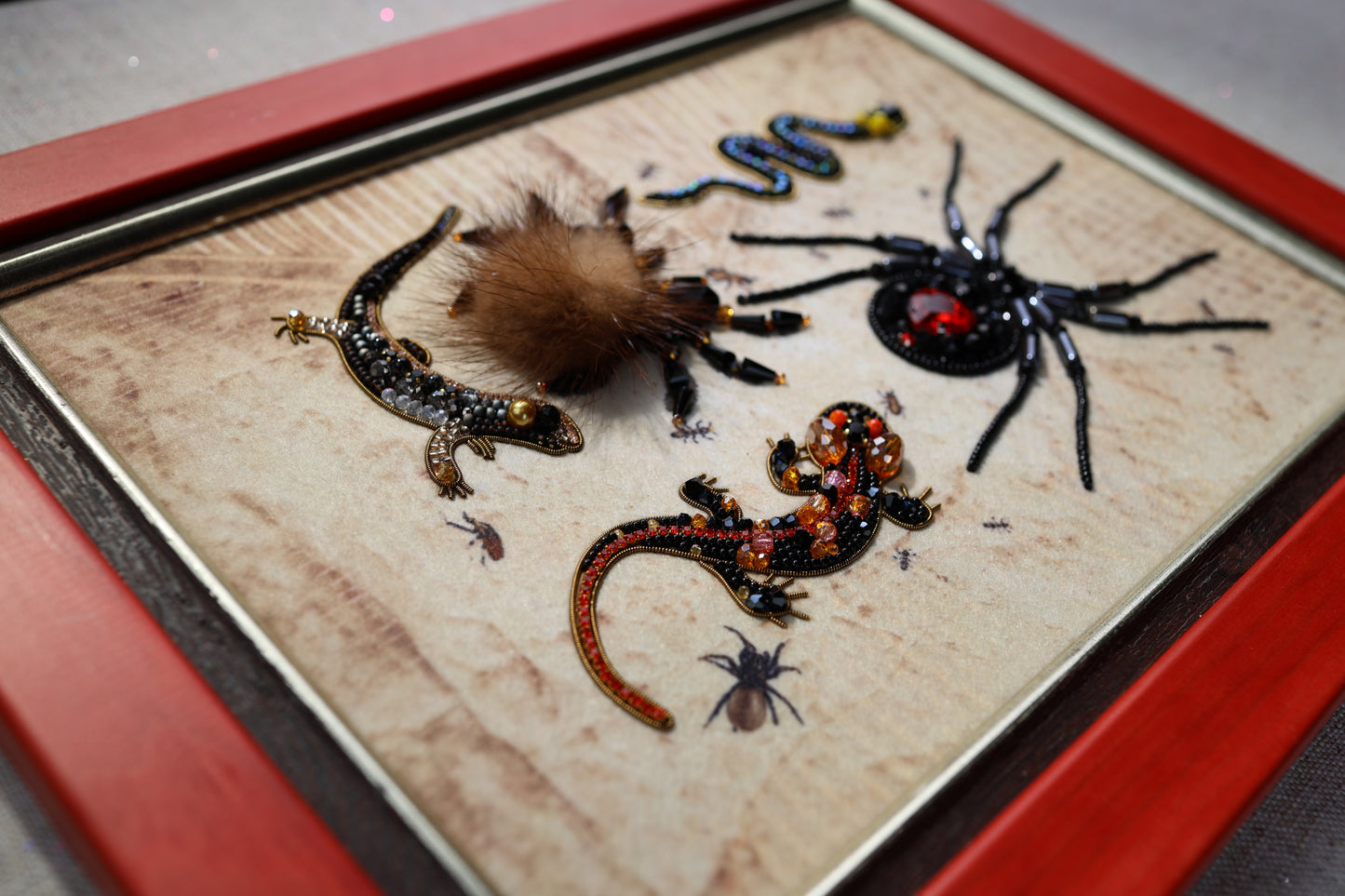 a close-up view of a framed collage of various insects and animals, including a spider, a lizard, and several other small creatures.