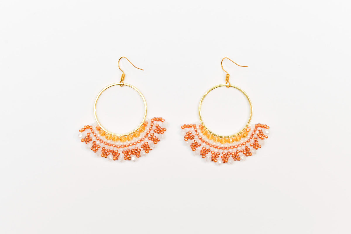 A pair of gold hoop earrings with a beaded design, featuring a circular hoop and a fringe of small beads in shades of orange and brown.