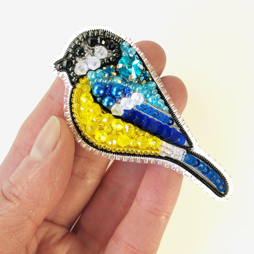 a hand holding a small bird brooch in it&#39;s left hand