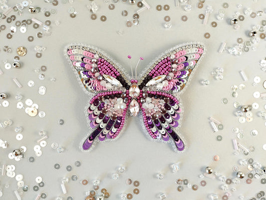 a pink butterfly brooch sitting on top of a table
