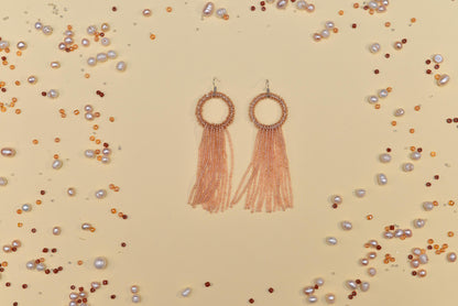 a pair of earrings with tassels and pearls