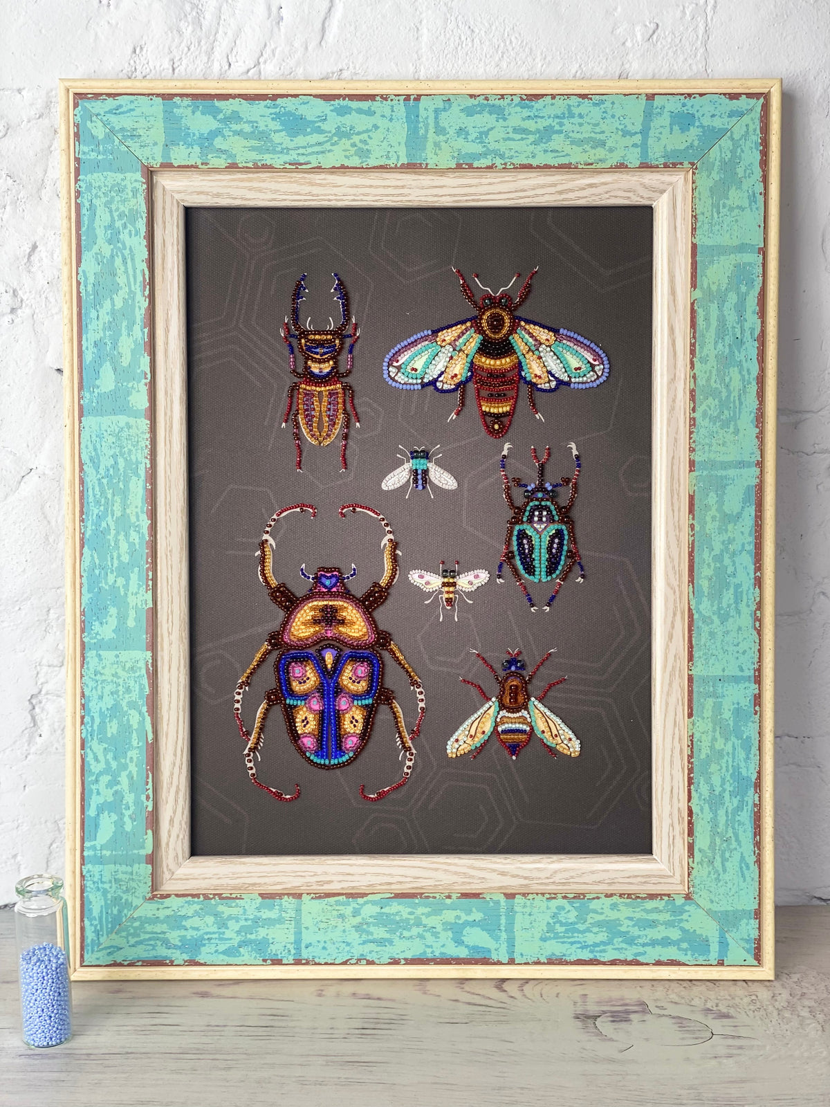 a framed collage of various colorful insects, including a large dragonfly, a bee, and several other insects, all set against a dark background.