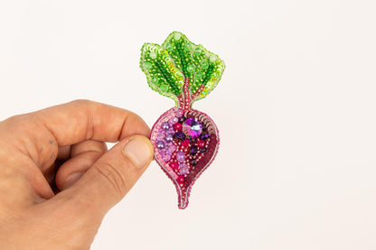 a hand holding a piece of art made out of beads