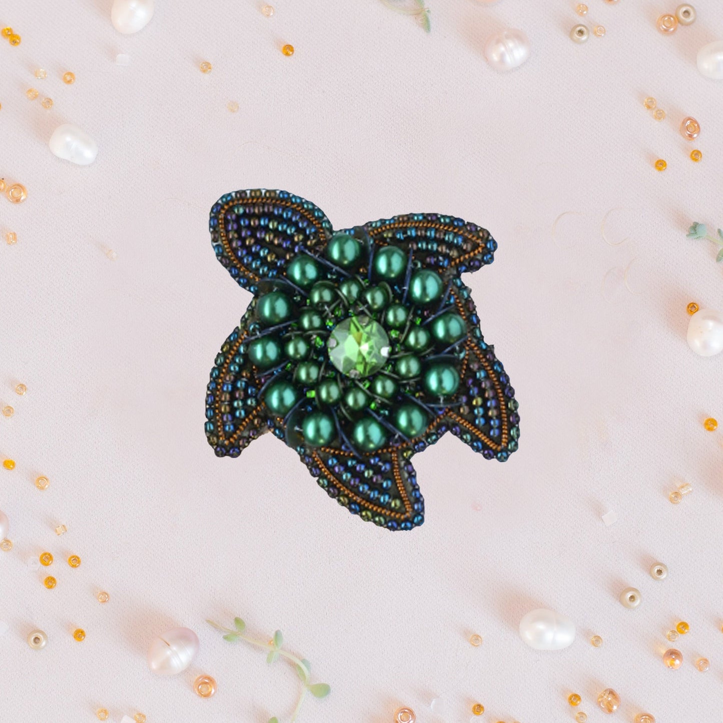 a green beaded brooch sitting on top of a table