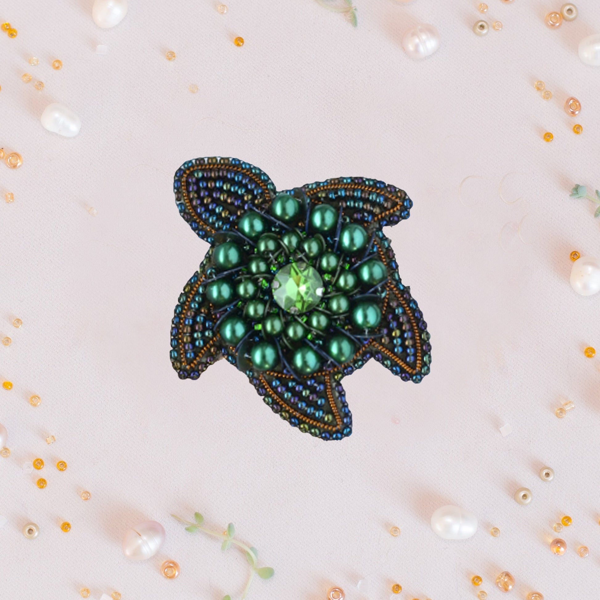 a green beaded brooch sitting on top of a table