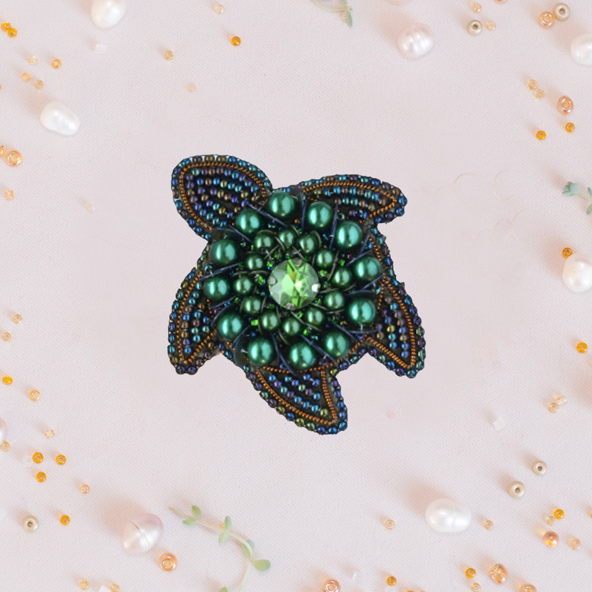 a green beaded brooch sitting on top of a table
