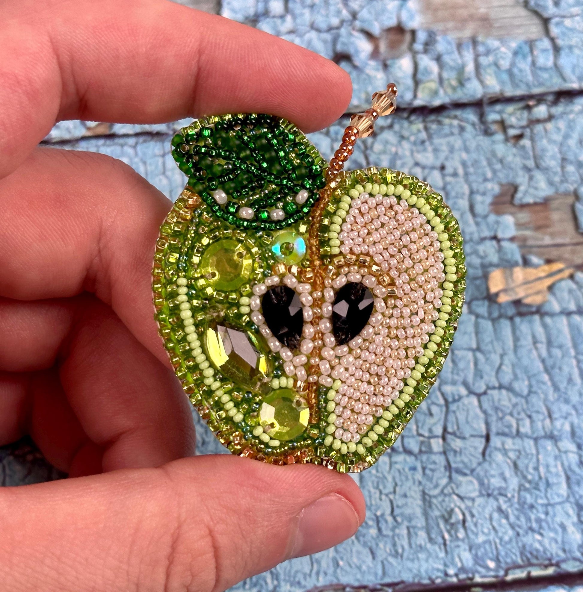 a hand holding a green apple with a face on it