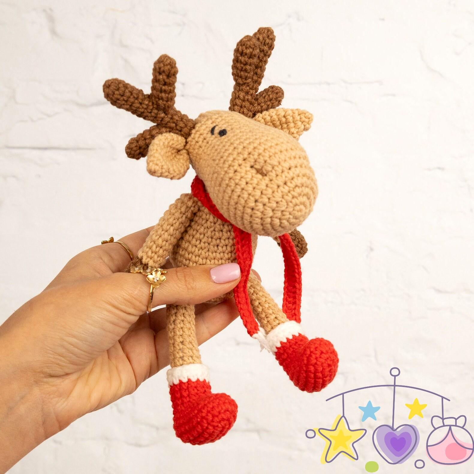 a hand holding a crocheted stuffed animal in front of a white wall