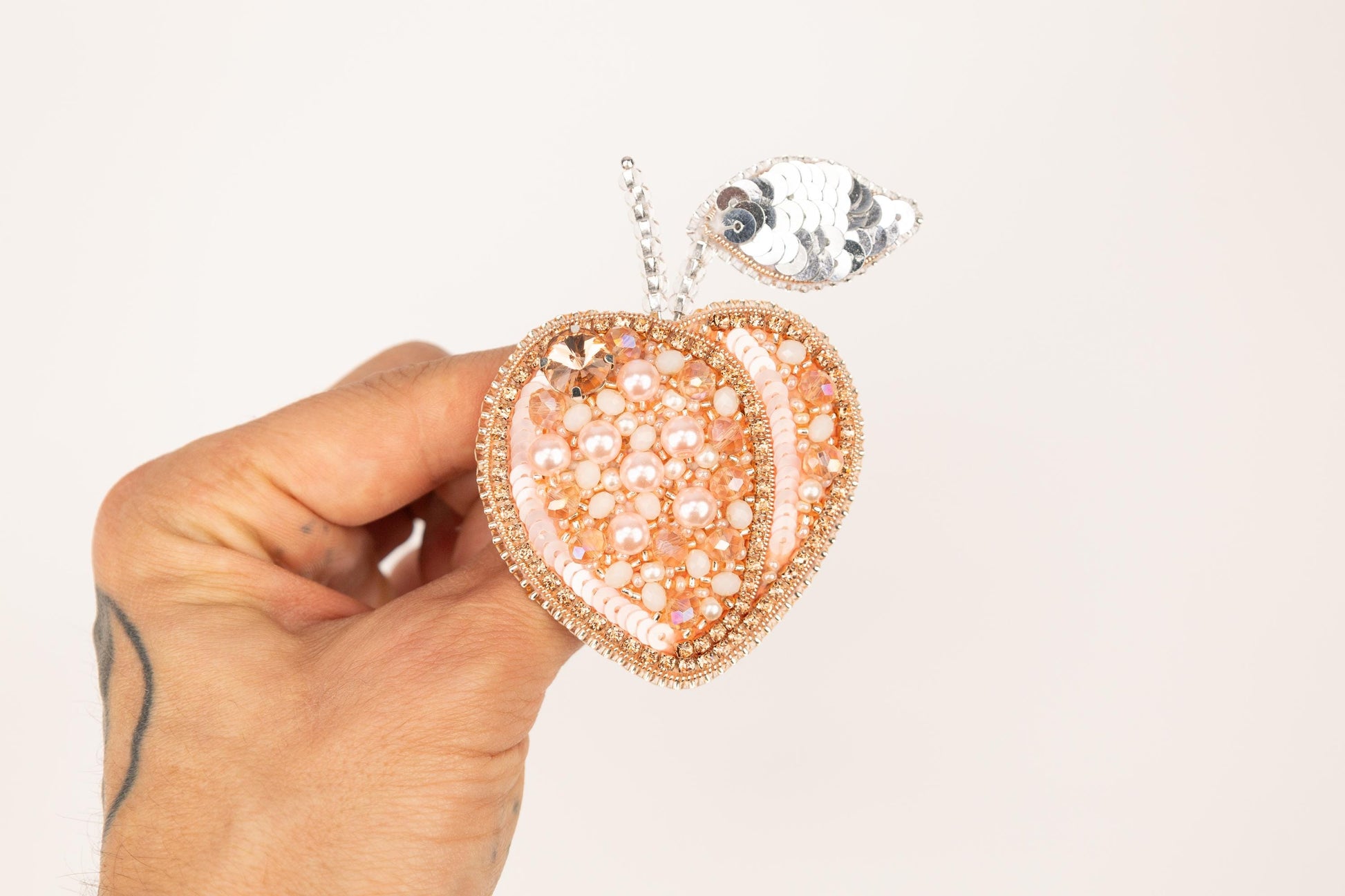a hand holding a pink and white heart shaped pendant