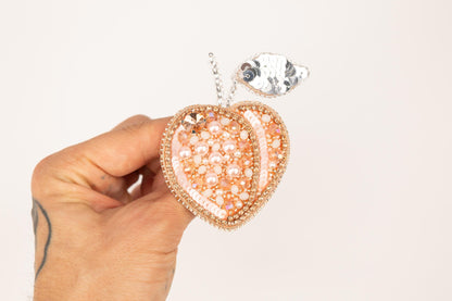 a hand holding a pink and white heart shaped pendant