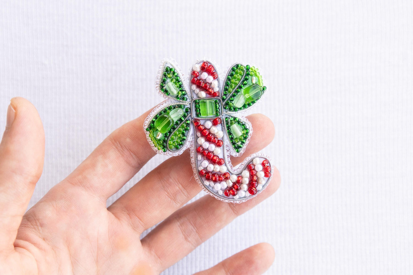 a hand is holding a green and red brooch