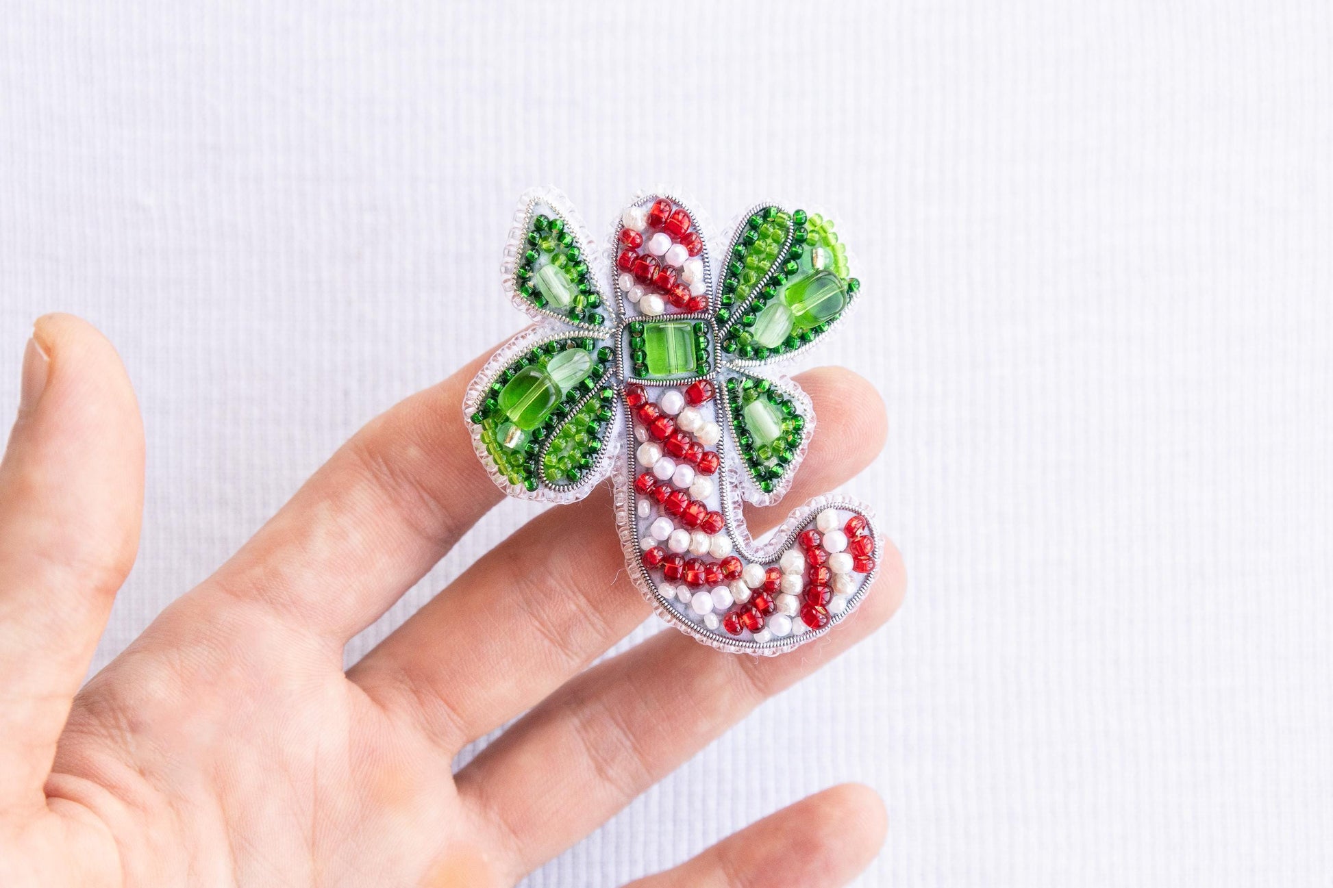 a hand is holding a green and red brooch