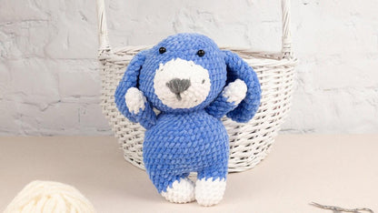 a blue and white stuffed animal sitting next to a ball of yarn