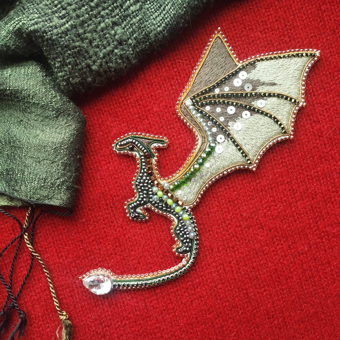 a dragon-shaped embroidered piece with a red background and a green and gold color scheme.