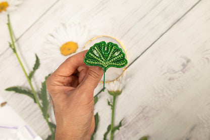 a person holding a green leaf in front of a flower
