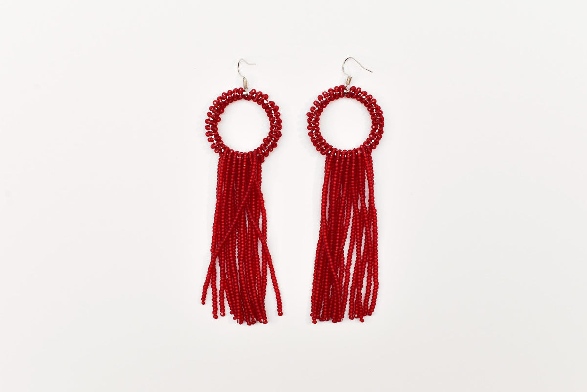 A pair of red beaded earrings with tassels hanging from the ends.