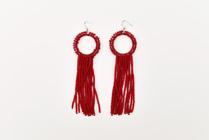 A pair of red beaded earrings with tassels hanging from the ends.