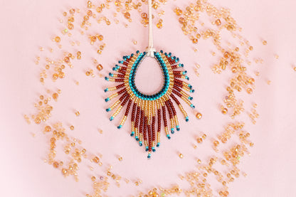 a beaded necklace with a large, colorful pendant, surrounded by scattered beads in various shades of gold, red, and blue.