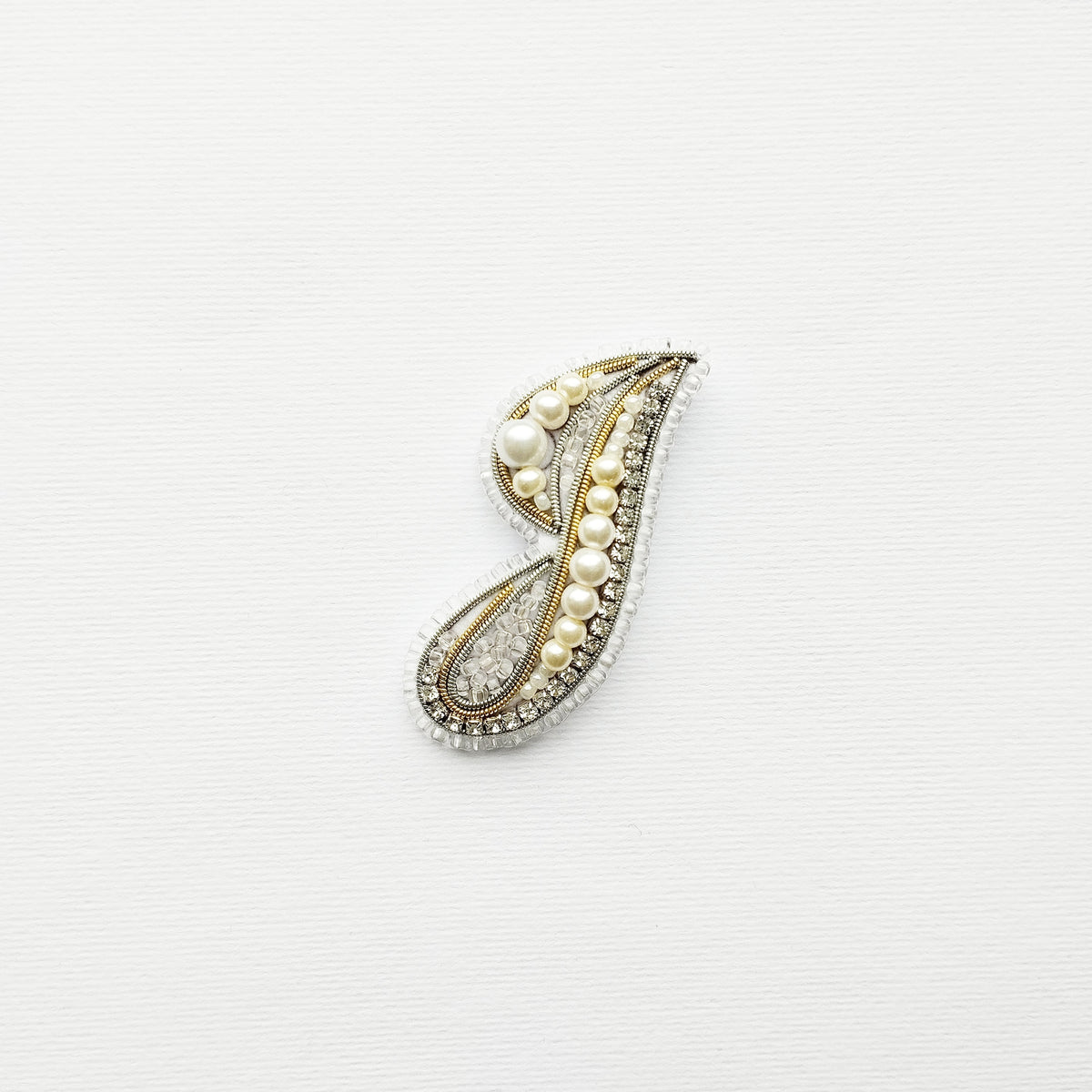 A decorative letter 'J' made of various materials, including pearls and crystals, is displayed against a white background.
