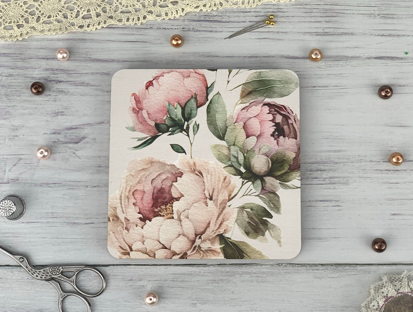 a coaster with flowers on it next to a pair of scissors